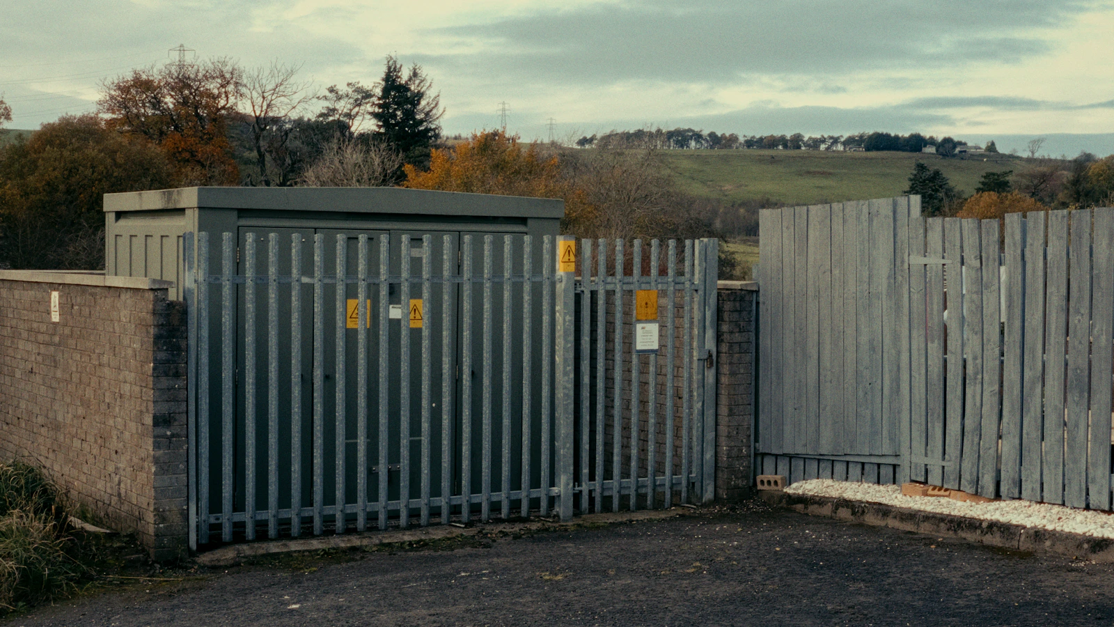 Metal security gate fitted beside a brick boundary wall